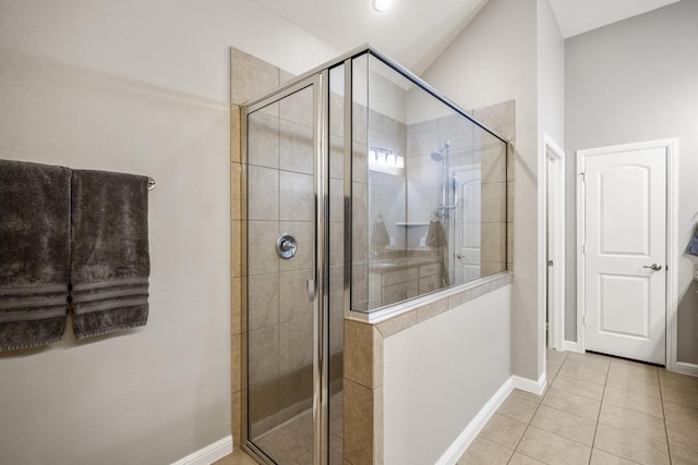 bathroom featuring lofted ceiling, a shower stall, baseboards, and tile patterned floors