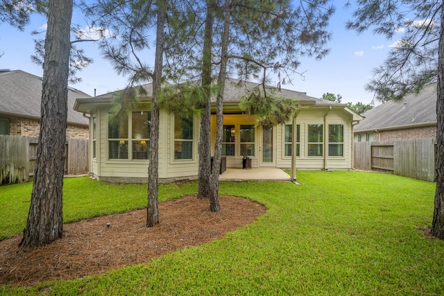 rear view of property featuring a lawn, a patio area, and a fenced backyard