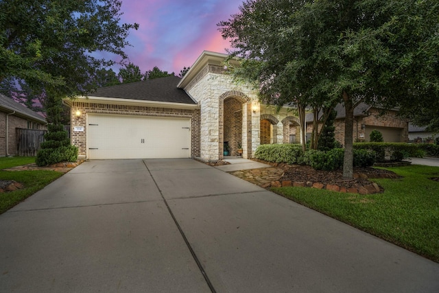 view of front of house with a garage, concrete driveway, brick siding, and stone siding