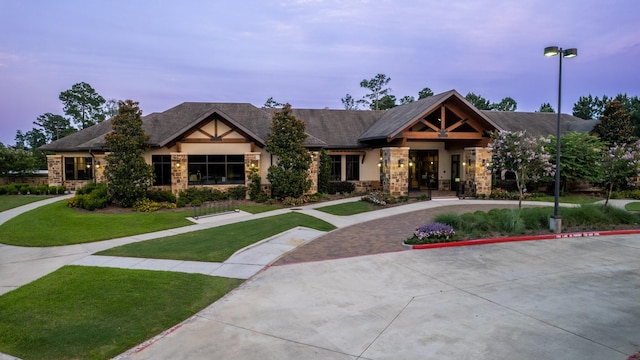 view of front of home with stone siding and a front lawn