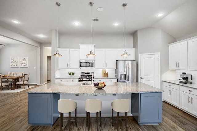 kitchen featuring visible vents, appliances with stainless steel finishes, white cabinets, and a breakfast bar area