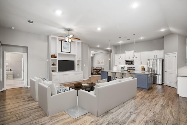 living area with light wood finished floors, lofted ceiling, recessed lighting, visible vents, and a ceiling fan