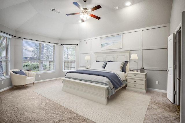 bedroom with ceiling fan, a decorative wall, light colored carpet, visible vents, and vaulted ceiling