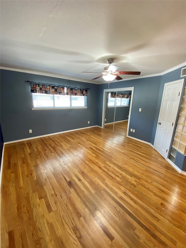 unfurnished bedroom featuring hardwood / wood-style floors, crown molding, multiple windows, and ceiling fan