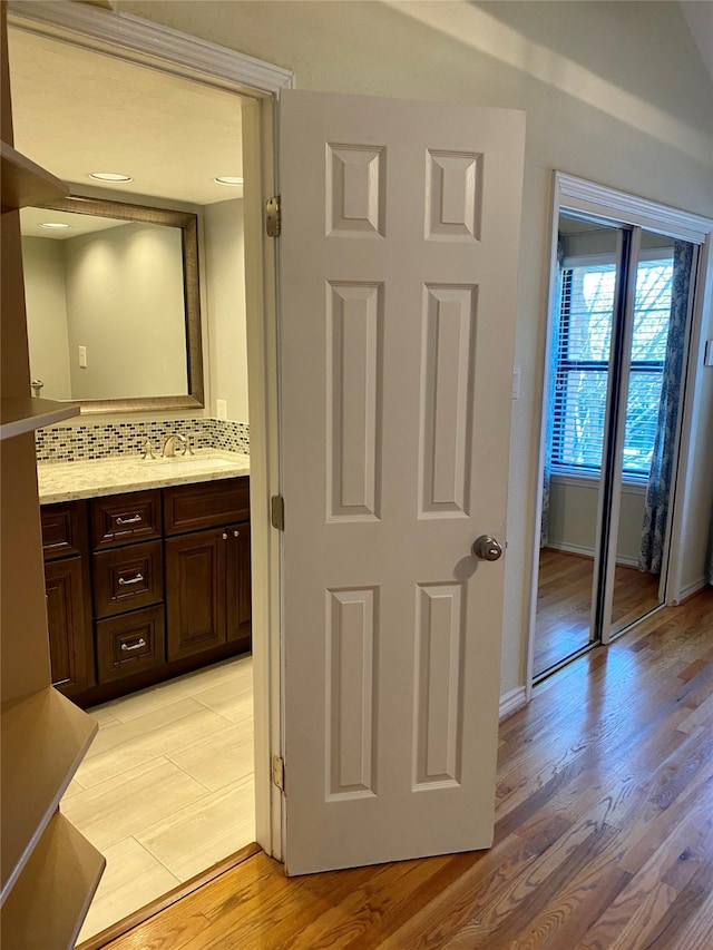 bathroom with vanity, hardwood / wood-style flooring, and tasteful backsplash