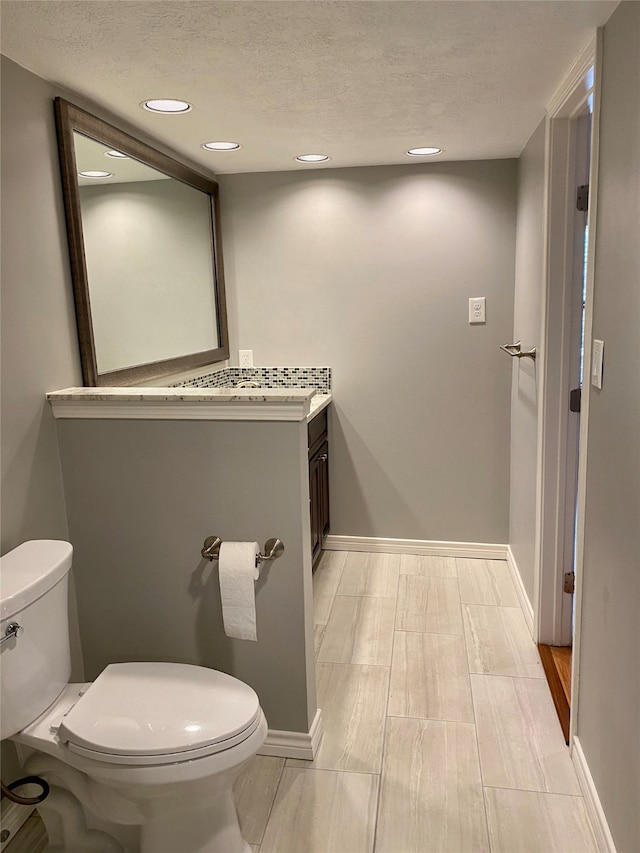 bathroom featuring toilet, a textured ceiling, and vanity