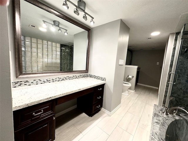 bathroom featuring toilet, backsplash, vanity, a textured ceiling, and an enclosed shower