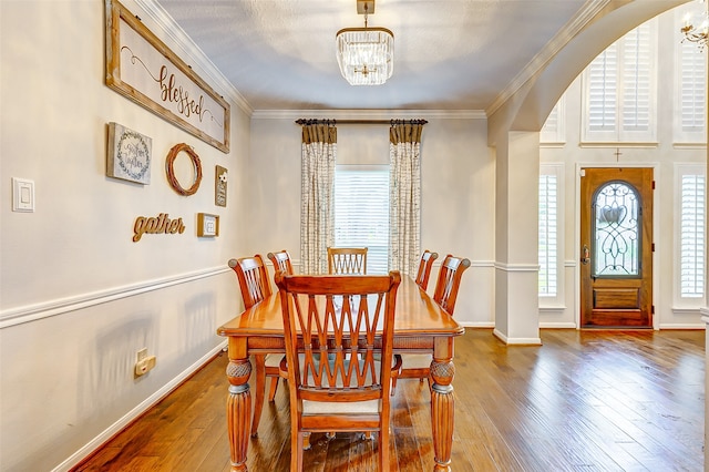 dining room featuring ornamental molding, hardwood / wood-style floors, and a notable chandelier