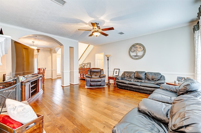 living room with crown molding, ceiling fan, hardwood / wood-style floors, and ornate columns