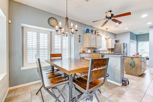 dining area with ceiling fan with notable chandelier, a textured ceiling, and light tile patterned floors