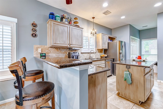 kitchen with backsplash, a kitchen breakfast bar, kitchen peninsula, sink, and stainless steel dishwasher