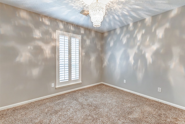 unfurnished room with carpet, a notable chandelier, and a textured ceiling