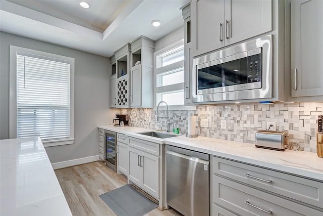 kitchen featuring light wood-type flooring, light stone countertops, stainless steel appliances, and sink