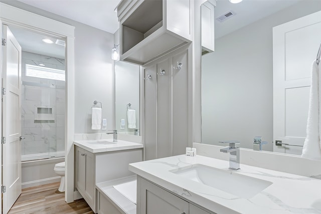 full bathroom featuring toilet, hardwood / wood-style flooring, bath / shower combo with glass door, and vanity