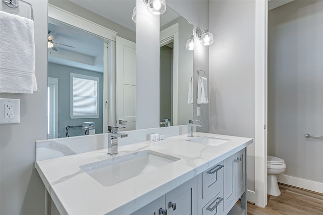 bathroom featuring vanity, toilet, hardwood / wood-style flooring, and ceiling fan