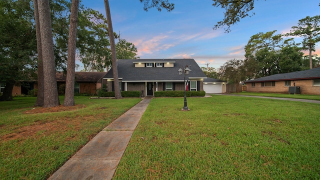 view of front facade with a yard, cooling unit, and a garage