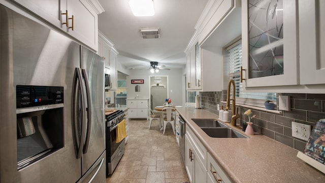 kitchen with ceiling fan, sink, tasteful backsplash, white cabinets, and appliances with stainless steel finishes