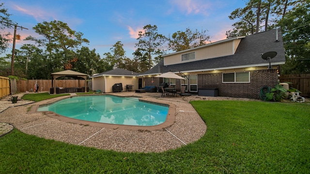 pool at dusk with a gazebo, a patio, and a yard