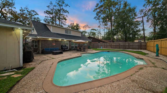 pool at dusk featuring outdoor lounge area and a patio