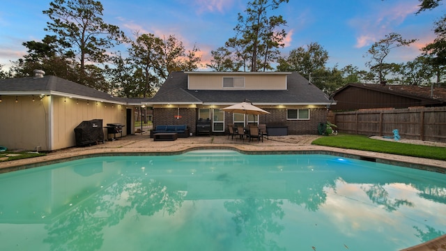 pool at dusk with a patio area and area for grilling