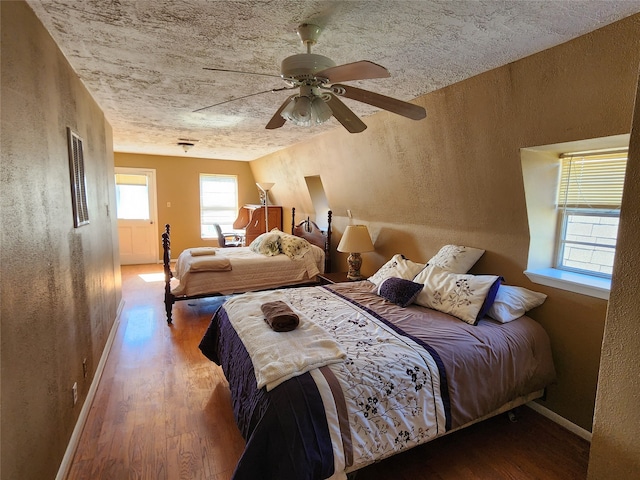 bedroom with hardwood / wood-style floors, ceiling fan, and a textured ceiling