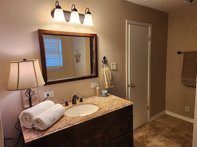 bathroom featuring baseboards, vanity, and a textured ceiling