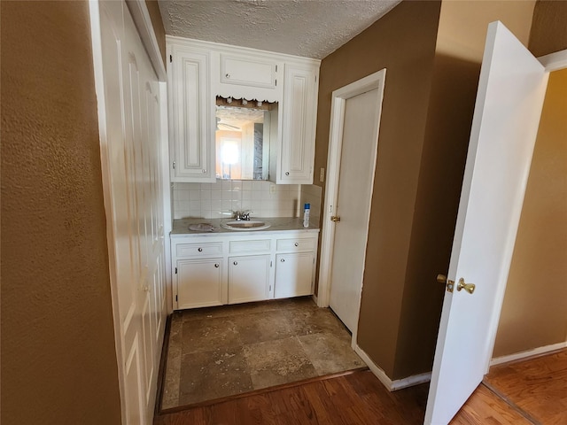 kitchen featuring dark wood-style flooring, tasteful backsplash, light countertops, white cabinets, and a sink