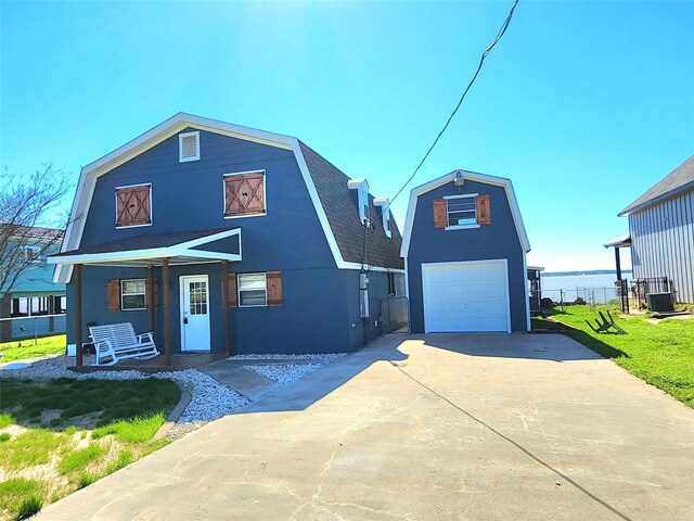 view of front of house with a front yard, a porch, a water view, cooling unit, and a garage