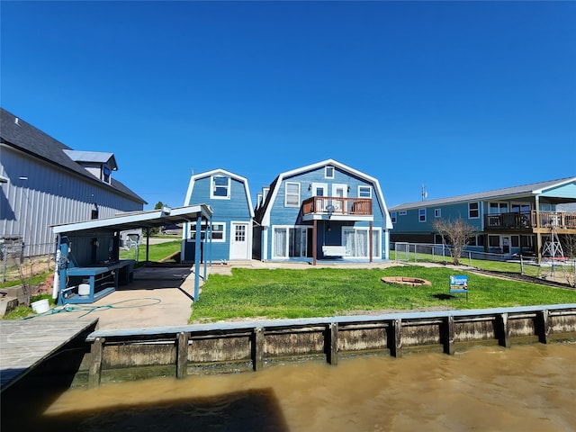 back of house featuring a patio area, a lawn, a balcony, and a water view