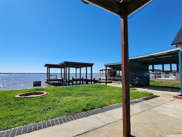 dock area with a water view, a yard, and a fire pit