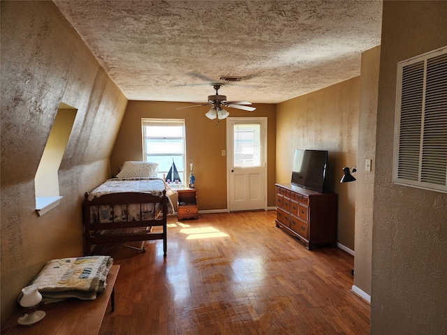 bedroom featuring hardwood / wood-style floors, ceiling fan, and a textured ceiling