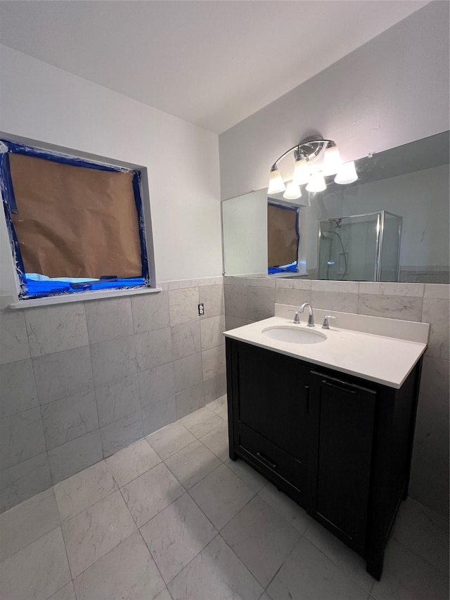 bathroom with vanity, tile walls, and a shower with shower door