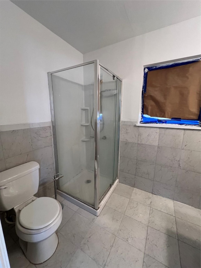 bathroom featuring tile walls, an enclosed shower, and toilet