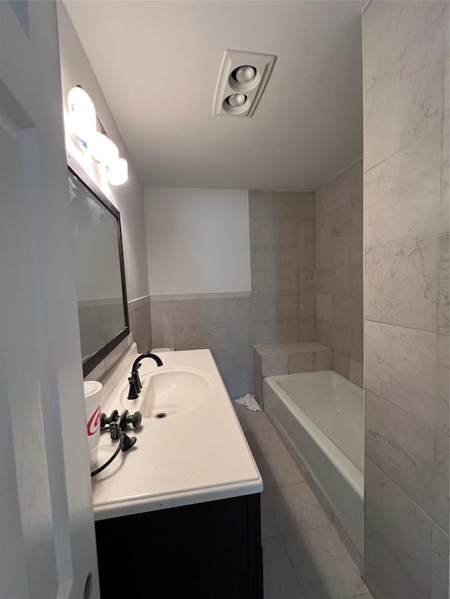 bathroom featuring a tub to relax in, vanity, and tile walls