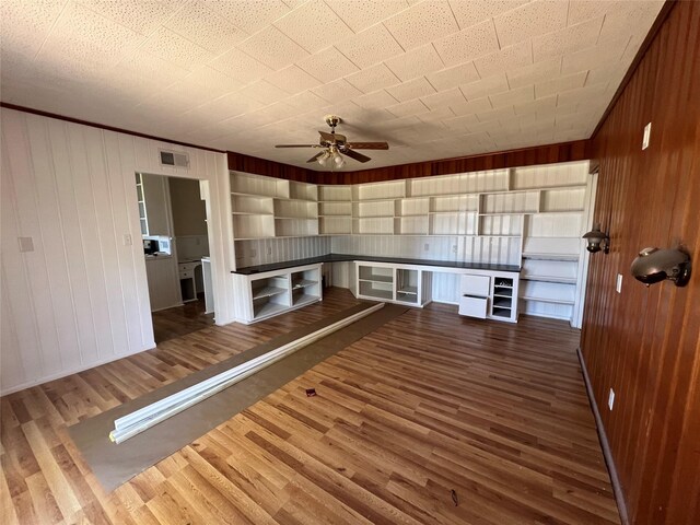 interior space featuring wooden walls, ceiling fan, and dark hardwood / wood-style floors