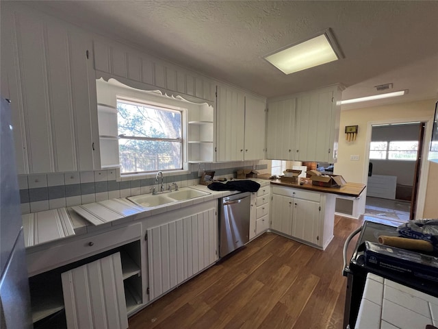 kitchen with white cabinetry, sink, stainless steel dishwasher, tile counters, and dark wood-type flooring