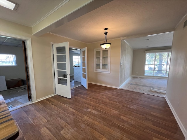 unfurnished dining area with ornamental molding, dark wood-type flooring, a textured ceiling, and french doors