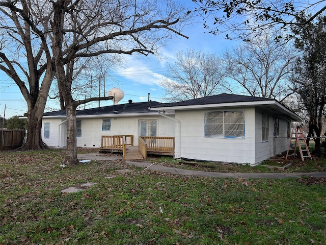 rear view of property featuring a wooden deck and a lawn