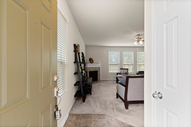 interior space with ceiling fan, a tiled fireplace, and light carpet