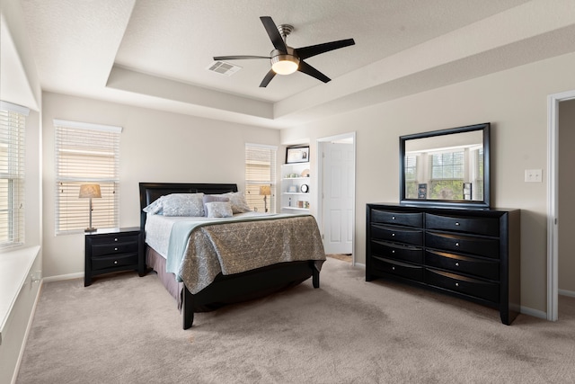 bedroom with carpet flooring, a raised ceiling, a textured ceiling, and ceiling fan