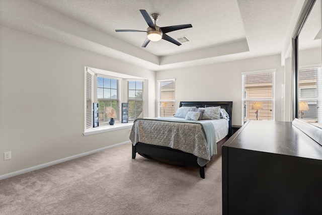 bedroom with a textured ceiling, a raised ceiling, ceiling fan, and carpet floors