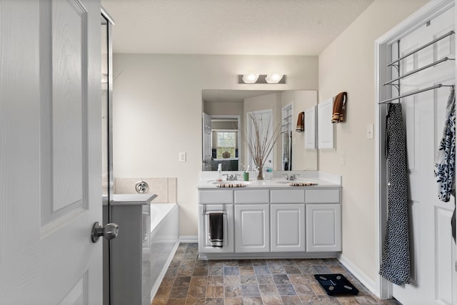 bathroom with vanity, a bath, and a textured ceiling