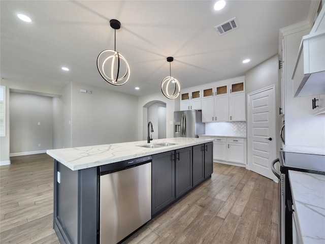 kitchen featuring a kitchen island with sink, white cabinetry, decorative light fixtures, sink, and appliances with stainless steel finishes