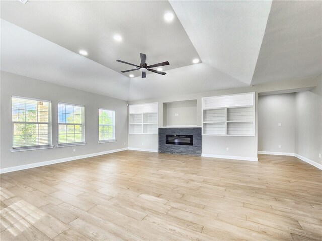 unfurnished living room with built in features, ceiling fan, lofted ceiling, and light hardwood / wood-style flooring