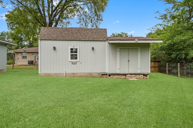 rear view of property with a storage unit, a lawn, and central AC unit