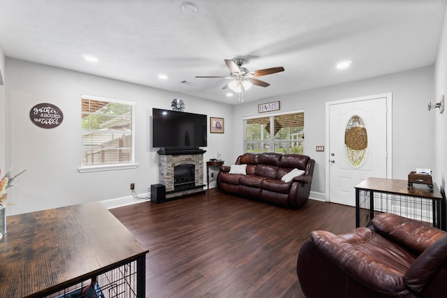 living room featuring a healthy amount of sunlight, ceiling fan, dark wood-type flooring, and a fireplace