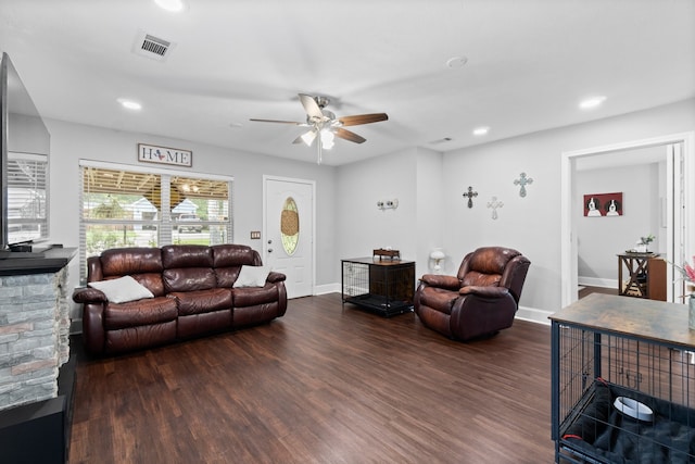 living room featuring a stone fireplace, ceiling fan, and dark hardwood / wood-style floors