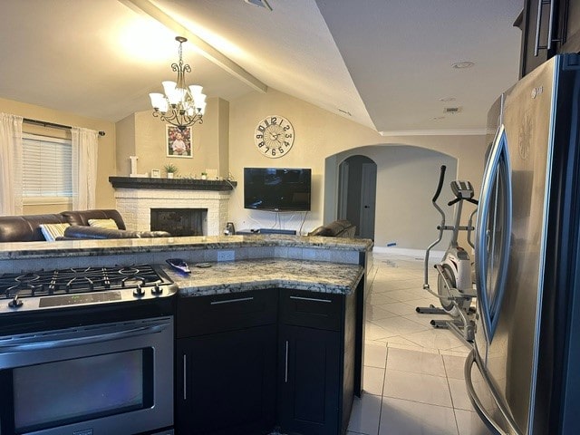 kitchen featuring vaulted ceiling, decorative light fixtures, light tile patterned floors, appliances with stainless steel finishes, and a chandelier