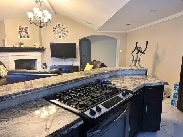 7410 Ashmole Ln, Houston, TX 77088 - kitchen featuring gas range oven, open floor plan, light stone countertops, lofted ceiling, and a brick fireplace