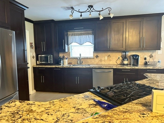 kitchen featuring light tile patterned floors, appliances with stainless steel finishes, tasteful backsplash, sink, and light stone counters